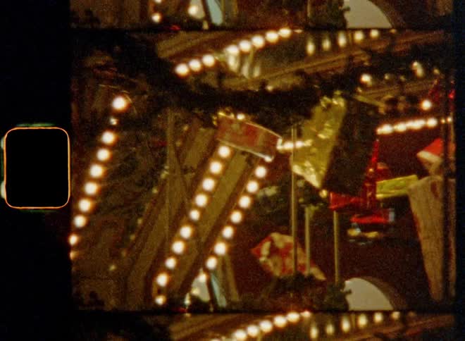 Wrapped gifts and Christmas decor spin around on a merry-go-round with colourful decorations and bright lights on a Christmas fair creating a heart-warming contemplative holiday atmosphere with a festive spirit on retro 8mm film footage