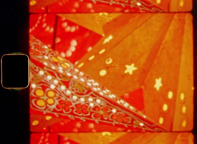 Super 8 mm film footage closeup of brightly colored paper star lanterns as Christmas decoration with colorful patterns are illuminated by warm light in a display of a market stall on art fair during advent season for holiday vibes
