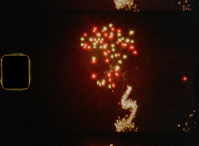 Dynamic handheld 8mm film of colourful fireworks exploding all over the night sky