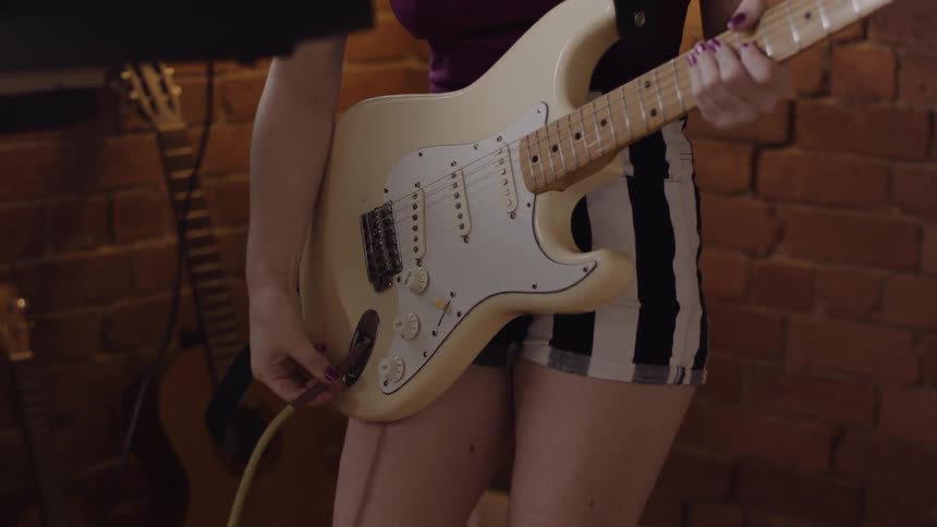 A woman in shorts plugs in a guitar