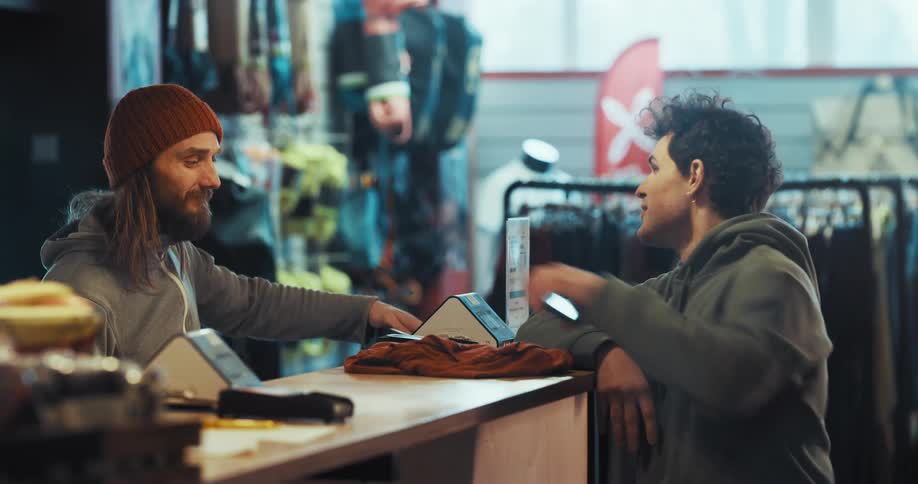 A man uses his smartphone to pay for clothing in a store and walks away