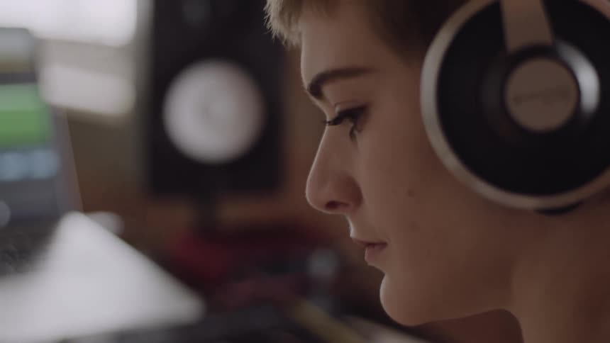 A woman is looking at a keyboard wearing headphones