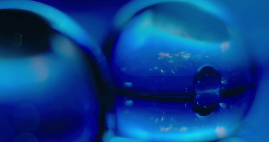 Blue light glows in the distance as the reflection of clear orbs shine inside other clear orbs