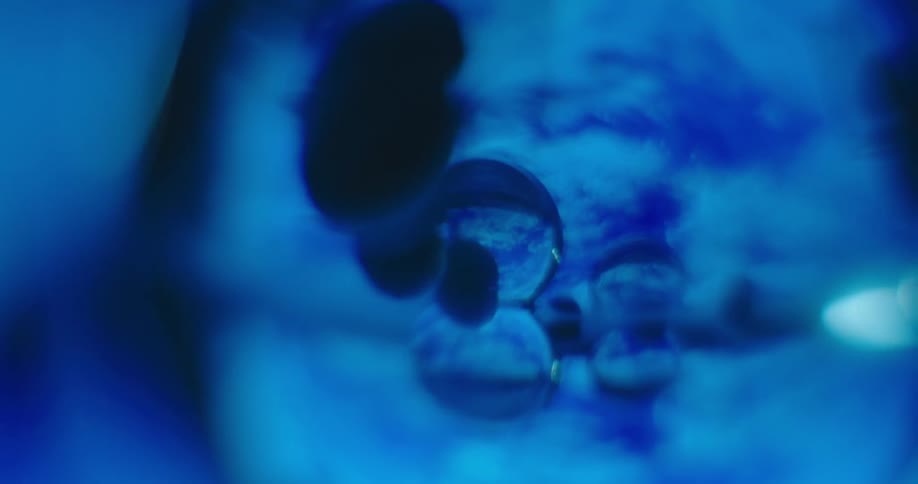 A surreal scene shows droplets of liquid which are refracting a blue background