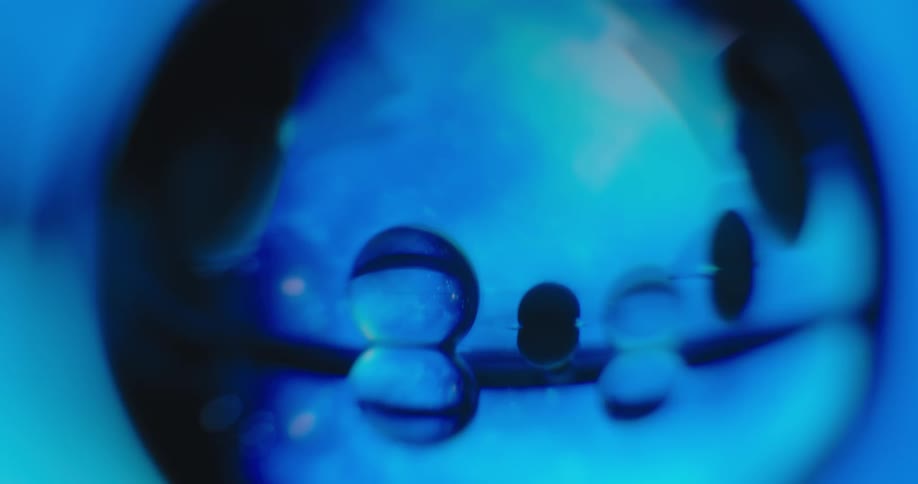 Blue light glows in the distance as the reflection of clear orbs shine in other clear orbs