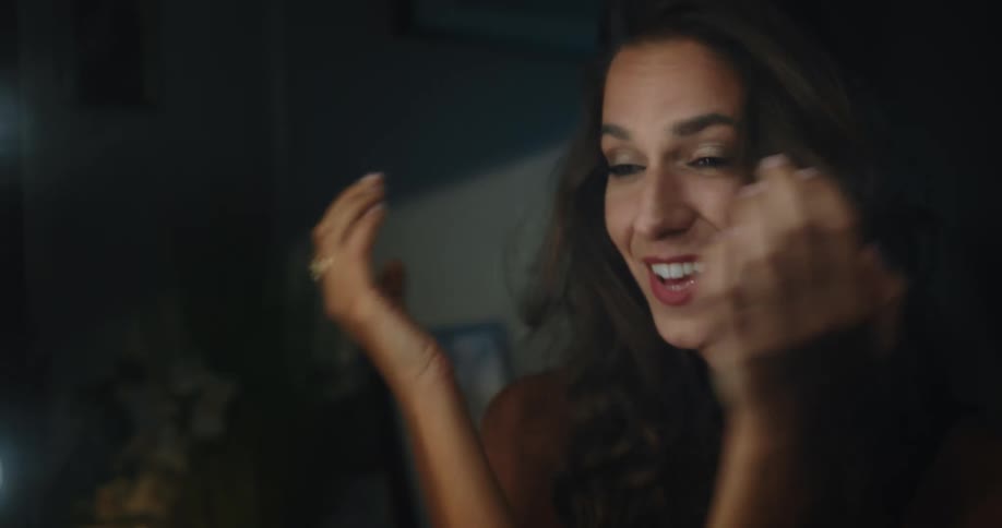A woman smiles and poses in front of a mirror while tossing her hair around