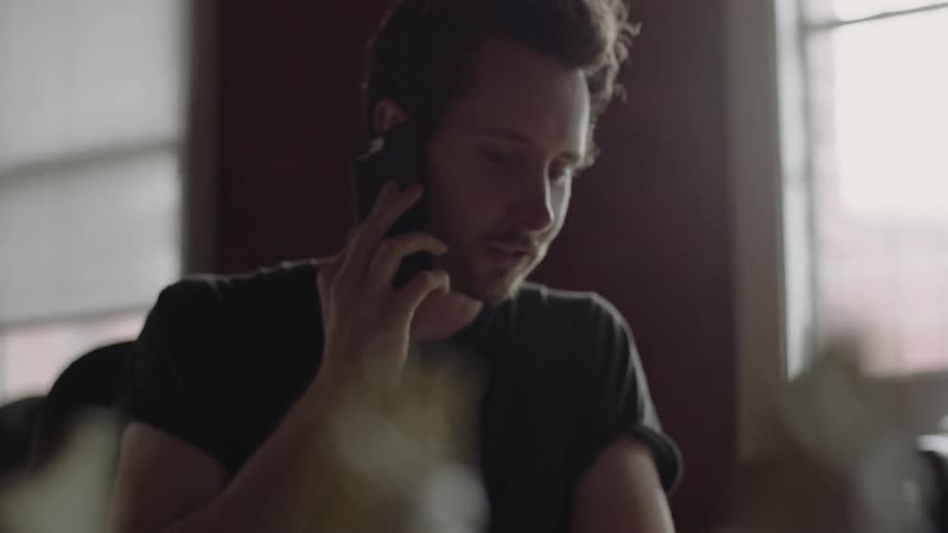 Man talking on a phone while sitting at a desk