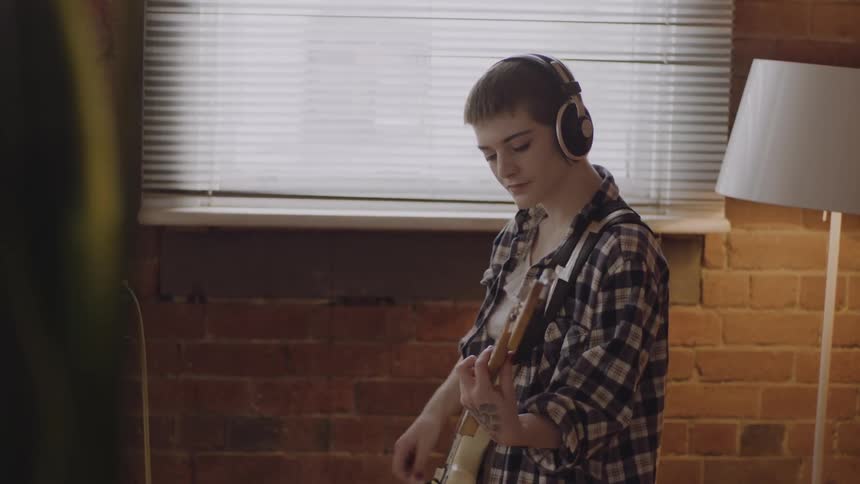 A woman playing an electric guitar in a music studio