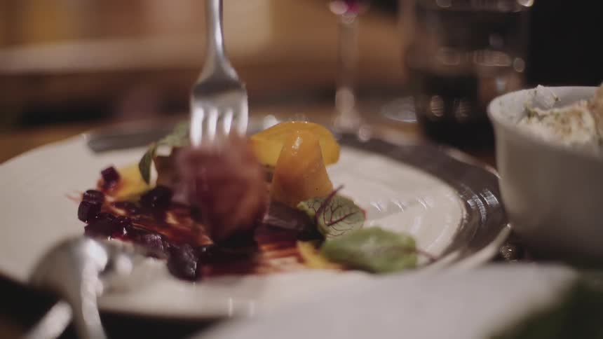 A person picks food from a plate using a fork
