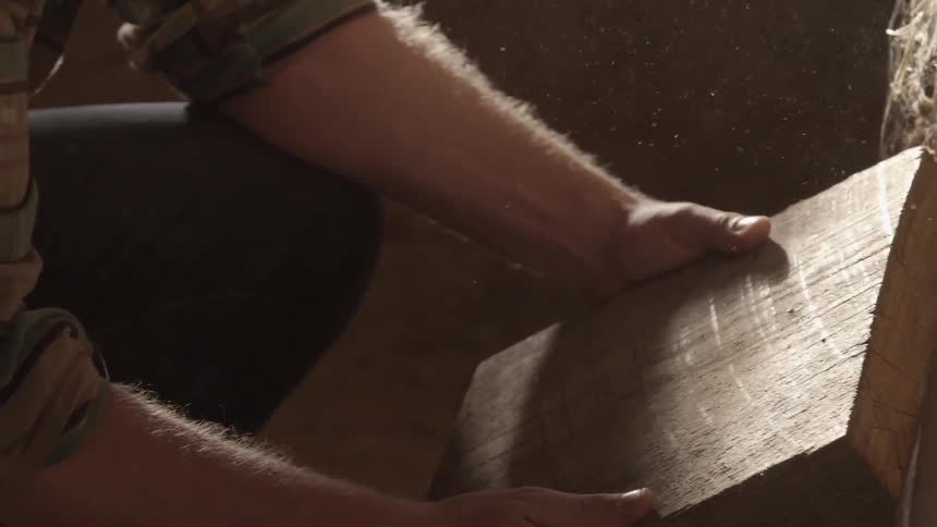A man picks up a block of wood and examines it
