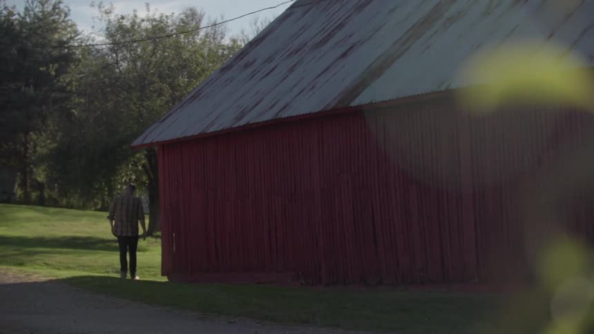 A man walks behind a barn