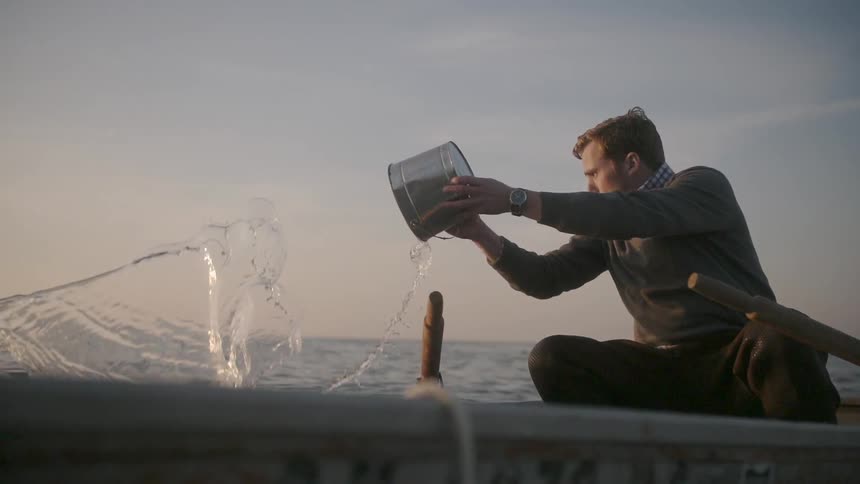 Man bailing water out of a small boat