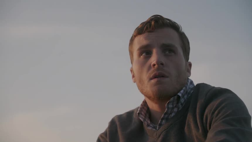 A man looks around outside at sunset