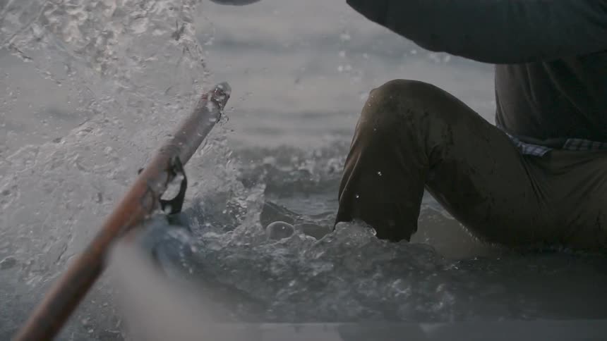 A man bails water from a canoe