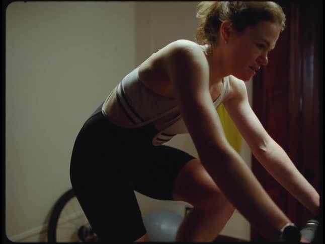 Light shines on a woman as she rides an exercise bike