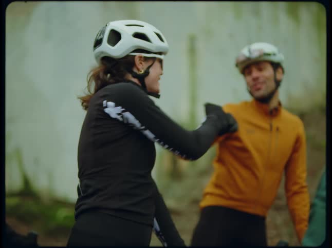Cyclists smile and exchange fist bumps during a brief stop