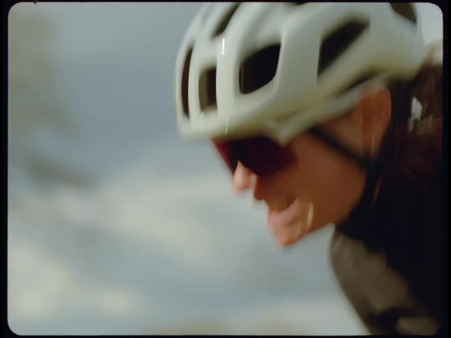 Woman wearing crash helmet grits her teeth while bumping across terrain