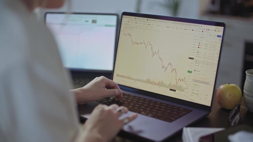 Female worker engages with graph on laptop while working remotely
