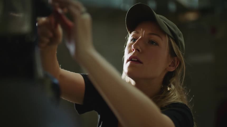 A woman is using tools and fixing something indoors