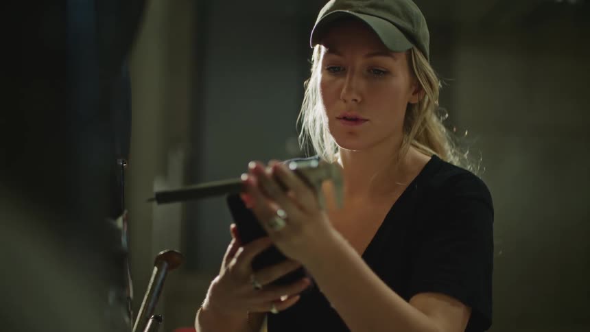 A woman holding her phone also takes measurements using a tool