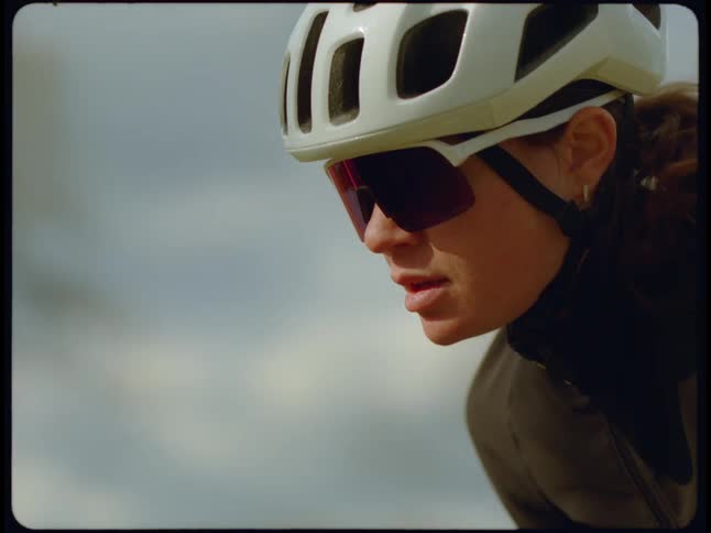A close up of a womans face wearing sunglasses and a white helmet and they move as it exercising