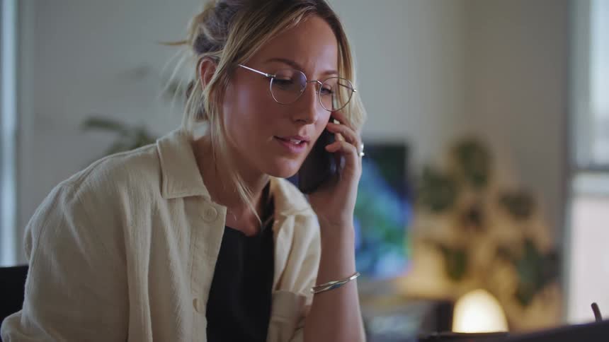 A woman is sitting down and talking on the phone