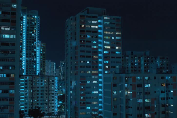 Lights in shades of blue flash inside futuristic towers and buildings as clouds move across the night sky