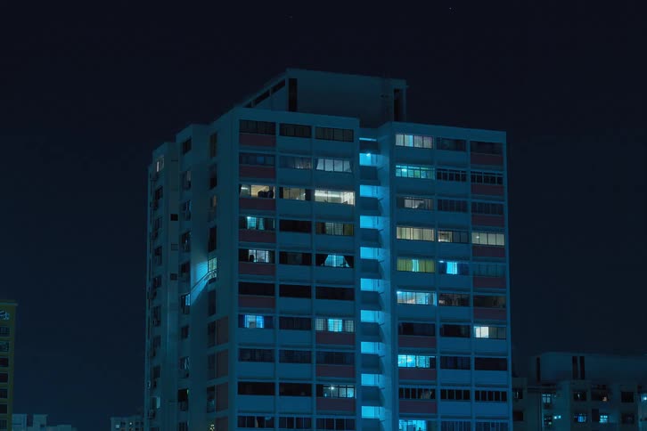 Lights flash inside futuristic buildings as clouds move across the night sky