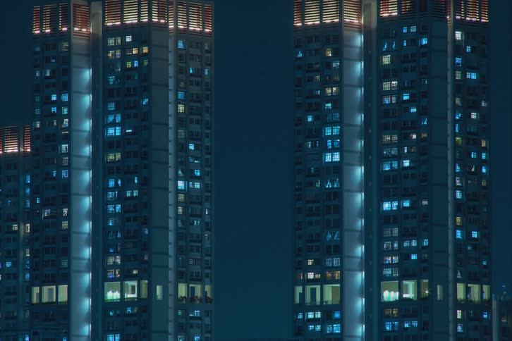 A group of building towers are blinking chaotically with blue lights against a blue background