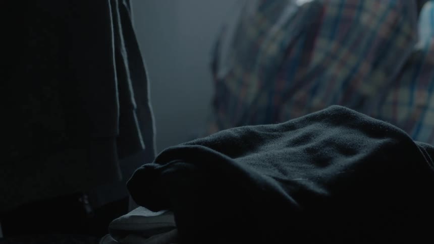 A person folding laundry and putting it in a pile