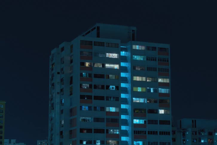 A time lapse of a city building with lights and screens flashing in the windows at night