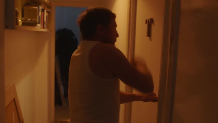 A man limps down the hall and bangs on the door