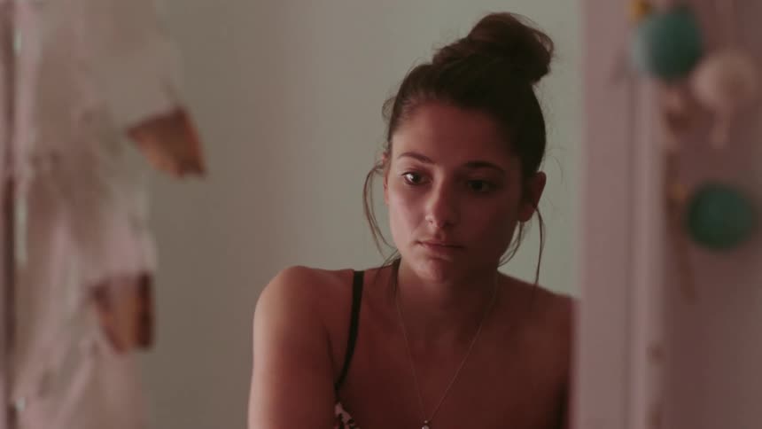 A woman is changing into a dress in front of a mirror