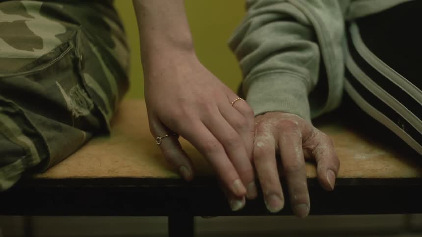 A woman gradually moves her hand along a bench and joins with an older mans hand