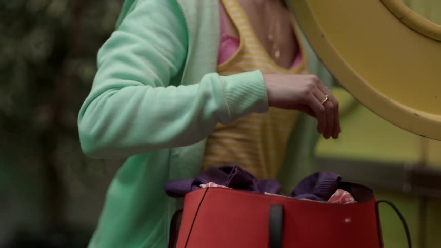 Woman packs clothes from dryer into bag then turns to stare