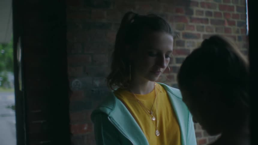 Two friends are talking to each other and standing by a building