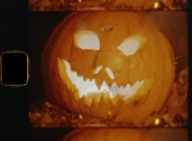 A dynamic and handheld close up of a carved pumpkin face with an angry facial expression followed by zooming out to reveal the evil smile and the angry eyes causing fear suspense and tension on vintage 8mm film with a nostalgic vibe