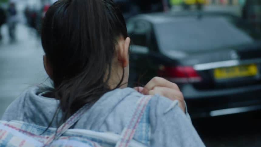 A woman carrying a large bag over her shoulder gets bumped into while walking