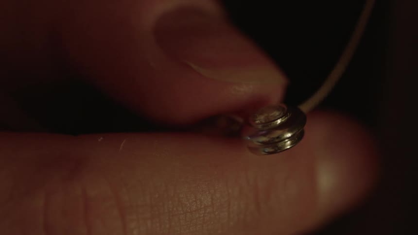 A woman fidgeting with a silver necklace pendant