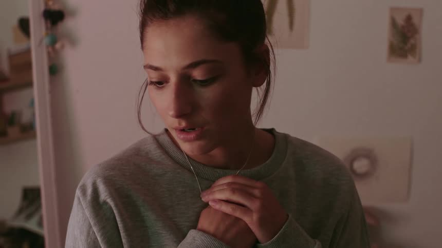 Woman with gray sweater holds her necklace and feels worried and nervous