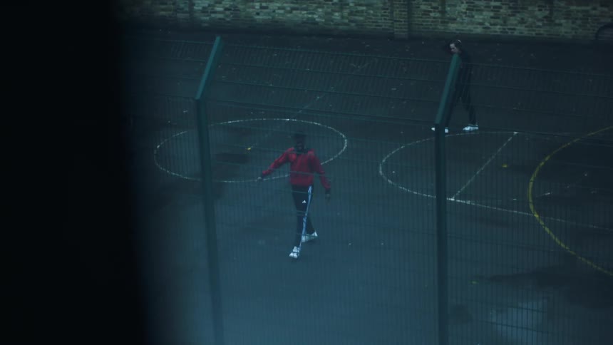 Three teenage boys kick a soccer ball around on a basketball court