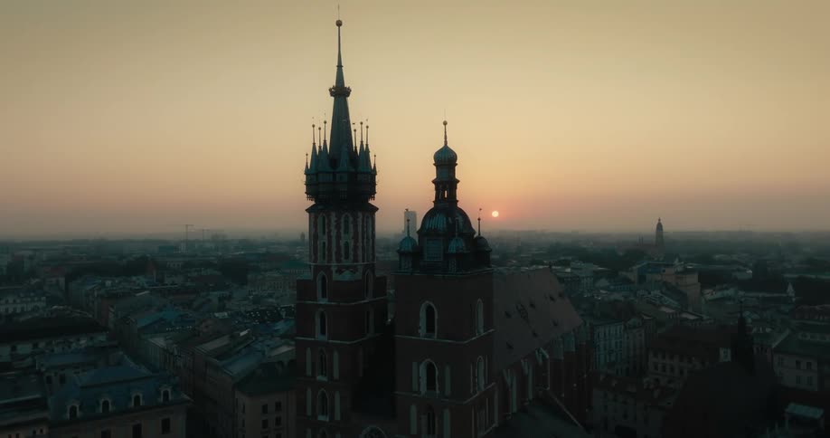 A clock tower against a dusk sky among other buildings