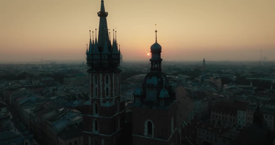 The sun is rising on the city behind gothic cathedral