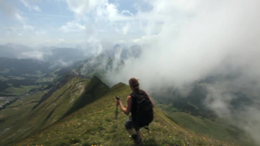 A female hiker is working her way down a mountain ridge