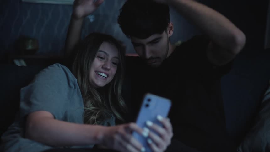 A young couple is taking pictures with there phone and goofing around