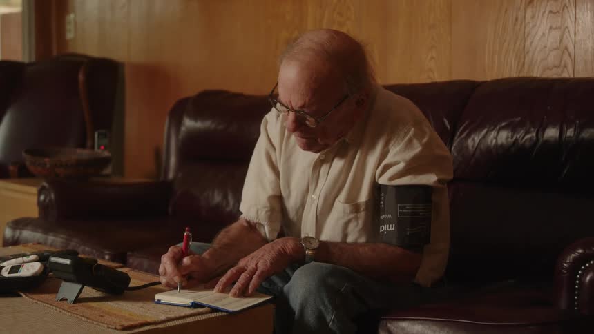 A man records his blood pressure in a notebook