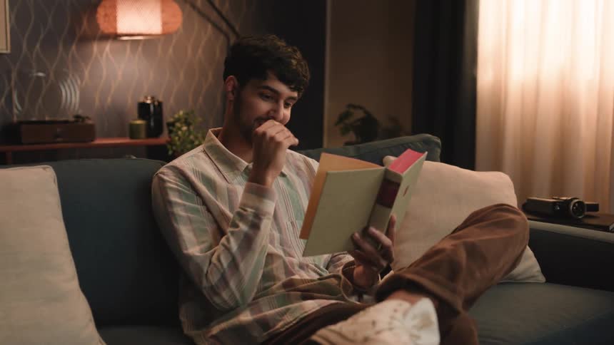 A man reads his book on the couch