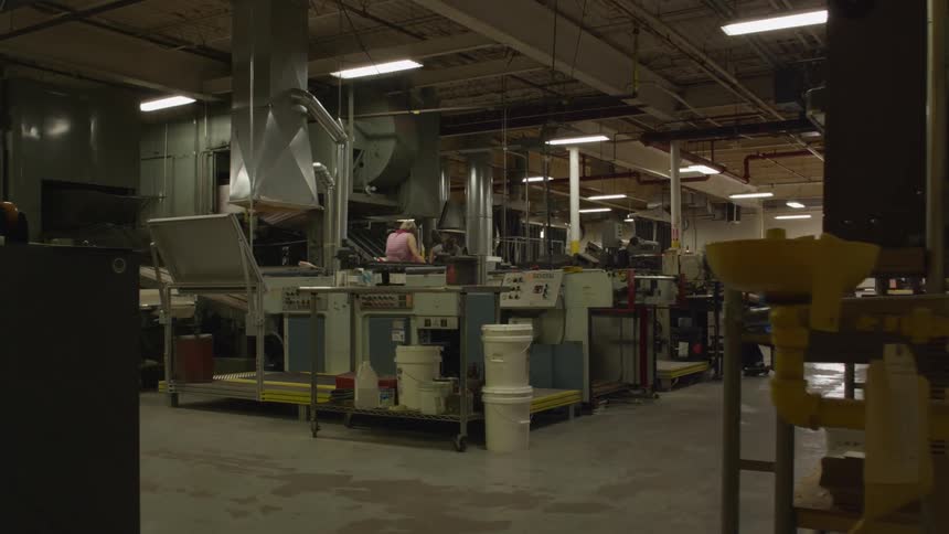 A woman is working in a factory near a conveyor