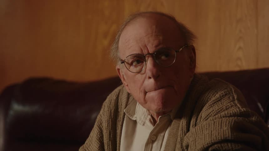 An elderly man is sitting on a couch indoors
