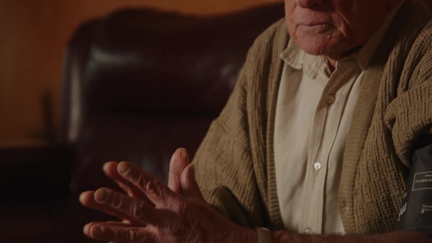 An elderly man is sitting down on the couch